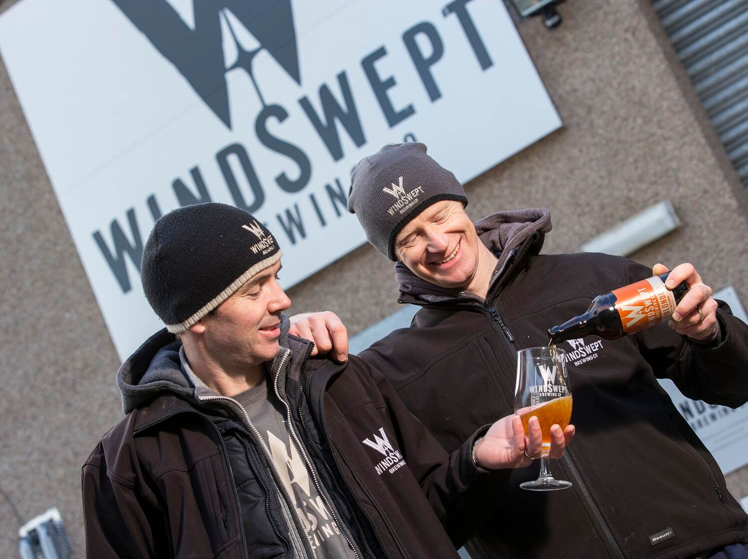 Staff members from Windswept Brewery pour drink into a glass