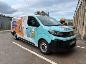 A transit van is covered with STEM Starts branding in bright block colours and characters depicting worker in hard hat and high vis.